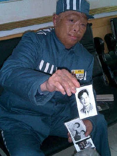 
Wang Jindong holds up a picture showing his former self during a government- organized visit for journalists to the prison in central China on Thursday. 
 (Associated Press / The Spokesman-Review)