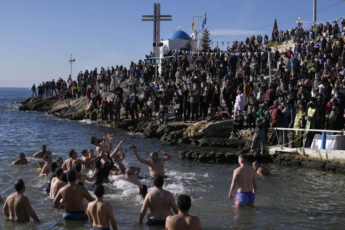 Pilgrims jump to catch the cross during a water blessing ceremony marking the Epiphany celebrations at Piraeus port, near Athens, Thursday, Jan. 6, 2022. Celebrations to mark the Christian holiday of Epiphany were canceled or scaled back in many parts of Greece Thursday as the country struggles with a huge surge in COVID-19 infections driven by the omicron variant.  (Thanassis Stavrakis)