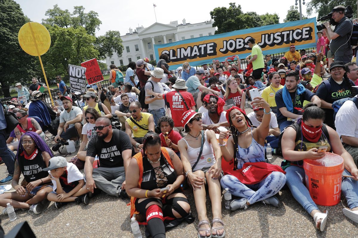 Demonstrators sit on the ground along Pennsylvania Ave. in front of the White House in Washington, Saturday, April 29, 2017, during a demonstration and march. Thousands of people gathered across the country to march in protest of President Donald Trump
