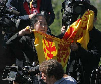 
Protester Wenyi Wang, 47, shouts and tries to hold up a banner from her position on the camera stand as Chinese President Hu Jintao, not pictured, speaks at the White House on Thursday. 
 (Associated Press / The Spokesman-Review)