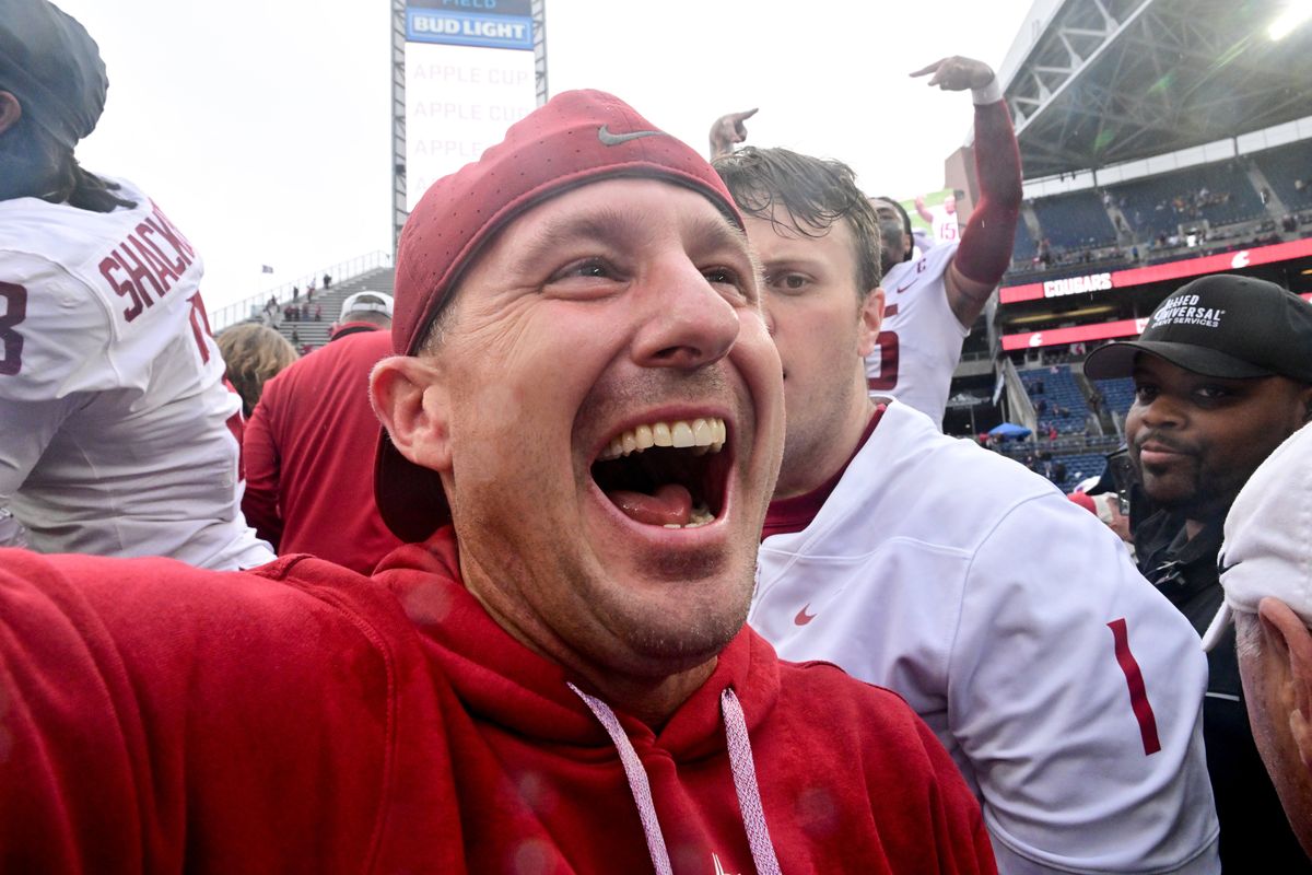 Washington State head coach Jake Dickert cheers as he is mobbed by fans after the Cougars defeated Washington on Sept. 14 in Seattle.  (Tyler Tjomsland/The Spokesman-Review)