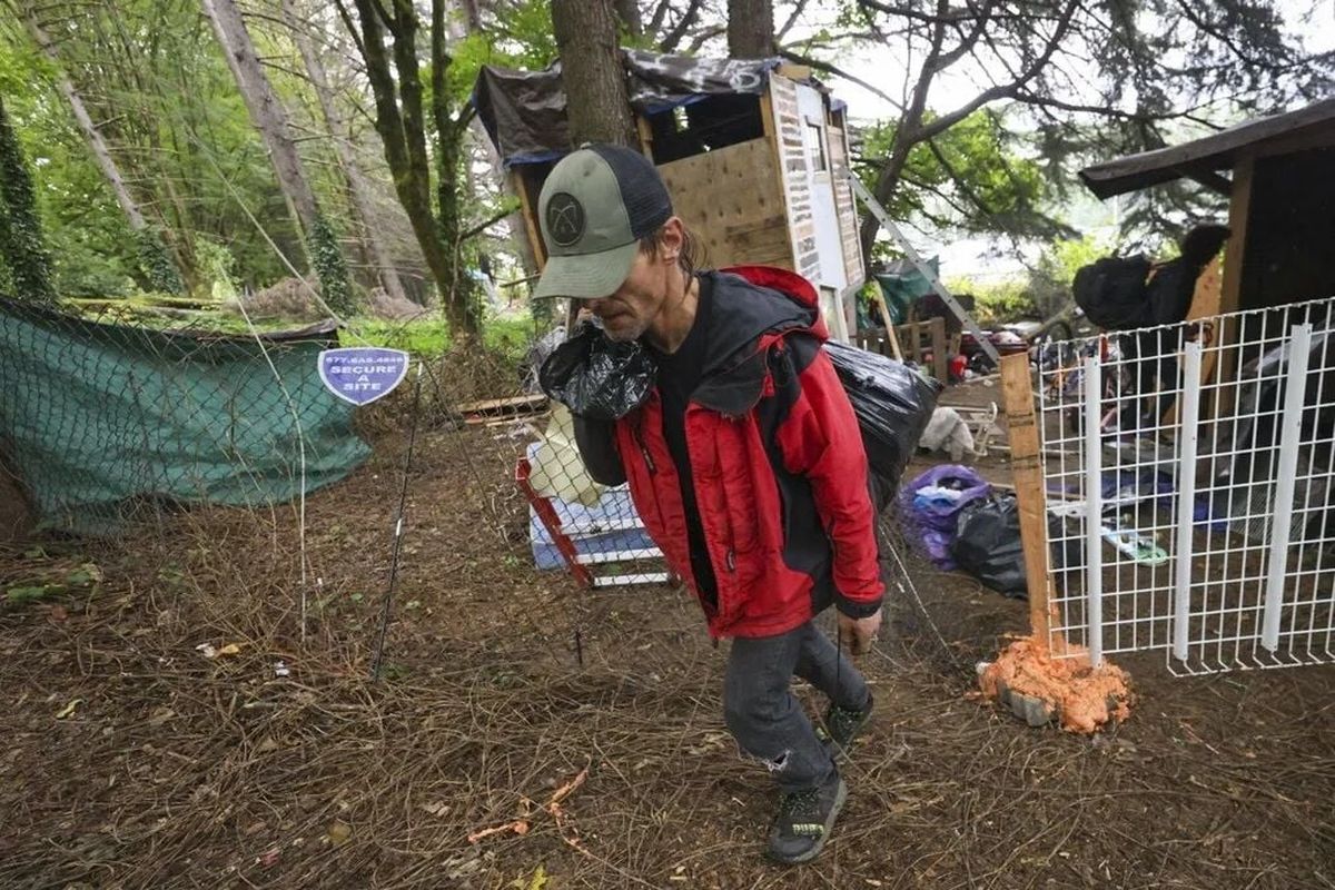 Garrett Hahn, 45, carries a bag of belongings away from where he lived at an encampment site under removal order on Sept. 25 in Seattle.  (Ivy Ceballo/Seattle Times)