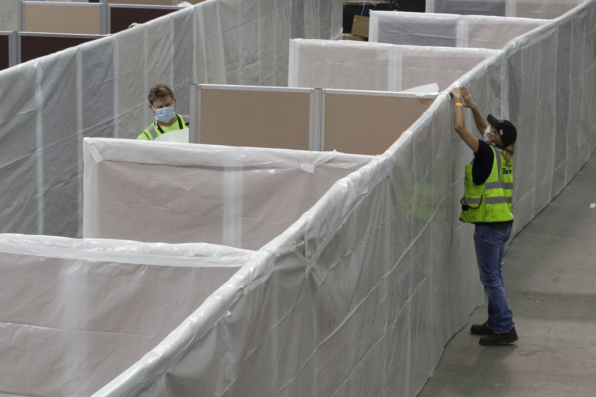 In this April 18, 2020 photo, sheeting is placed on partitions installed between beds as work is performed to turn the Sleep Train Arena into a 400 bed emergency field hospital to help deal with the coronavirus , in Sacramento, Calif. California spent nearly $200 million to set up, operate and staff alternate care sites that ultimately provided little help when the state’s worst coronavirus surge spiraled out of control last winter, forcing exhausted hospital workers to treat patients in tents and cafeterias.  (Rich Pedroncelli)