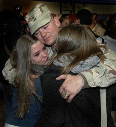 
Sgt 1st Class Rob Stewart hugs his daughters Kristen, 15, left, and Meghan, 17, at the Walter French Academy Bldg. in Lansing, Mich., after returning from Iraq recently. The military is stepping up efforts to educate personnel on financial well-being.
 (Associated Press / The Spokesman-Review)