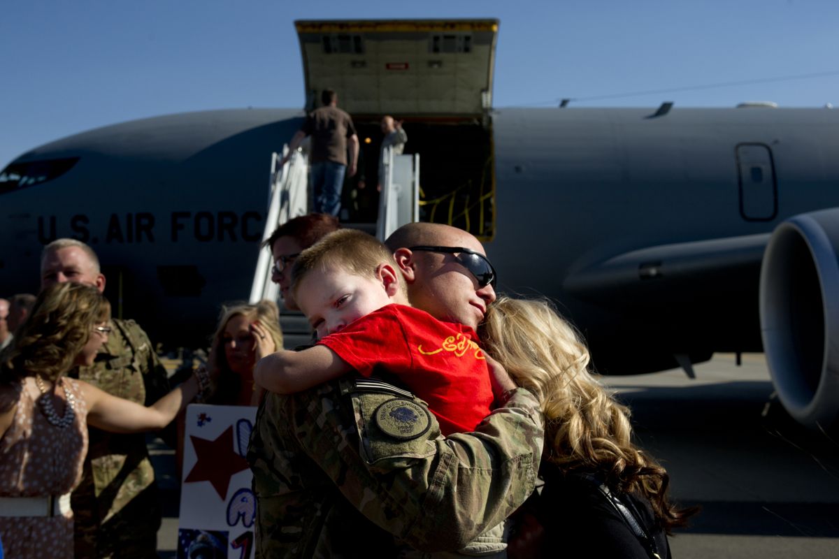 Derek Reese, of the Washington Air National Guard, holds his 3-year-old son, Ryan, and his wife, Michelle, after landing at Fairchild Air Force Base on Monday. Reese was deployed to Afghanistan for six months and was among some 30 airmen returning home. (Tyler Tjomsland)
