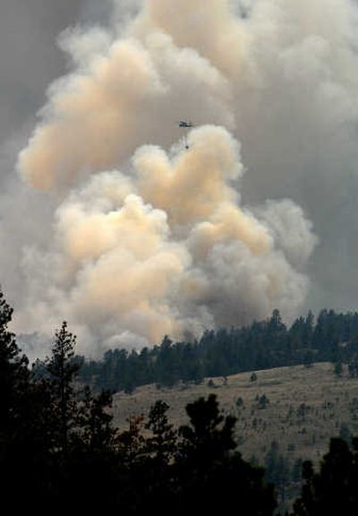 
A helicopter goes to refill its water bucket  near the edge of a wildfire southwest of Hot Springs, S.D., on Sunday. Associated Press
 (Associated Press / The Spokesman-Review)