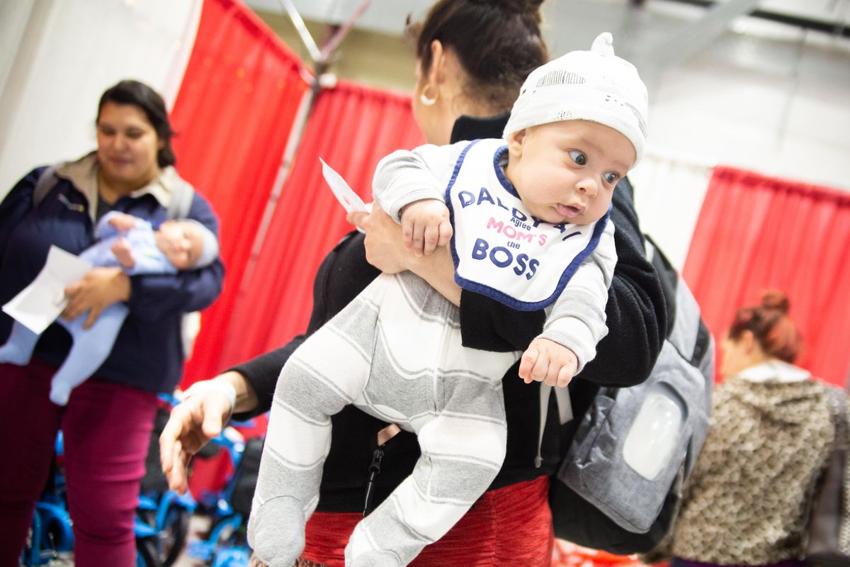 Three-month-old Isaac Suerez looks around curiously as his mom, Oxidia Leon, speaks to her sister-in-law Sarahi Castillo, holding her own two-month-old Caleb Suerez, during day two of the 2019 Christmas Bureau on Thursday, Dec. 12 in at the Spokane County Fair and Expo Center. The Christmas Bureau is open from 10 to 2:30 p.m. daily except Sunday through Dec. 20, and does not require proof of income, though adults need to bring proof of address and identity, and kids 17 and younger need to have correlating documents. (Libby Kamrowski / The Spokesman-Review)