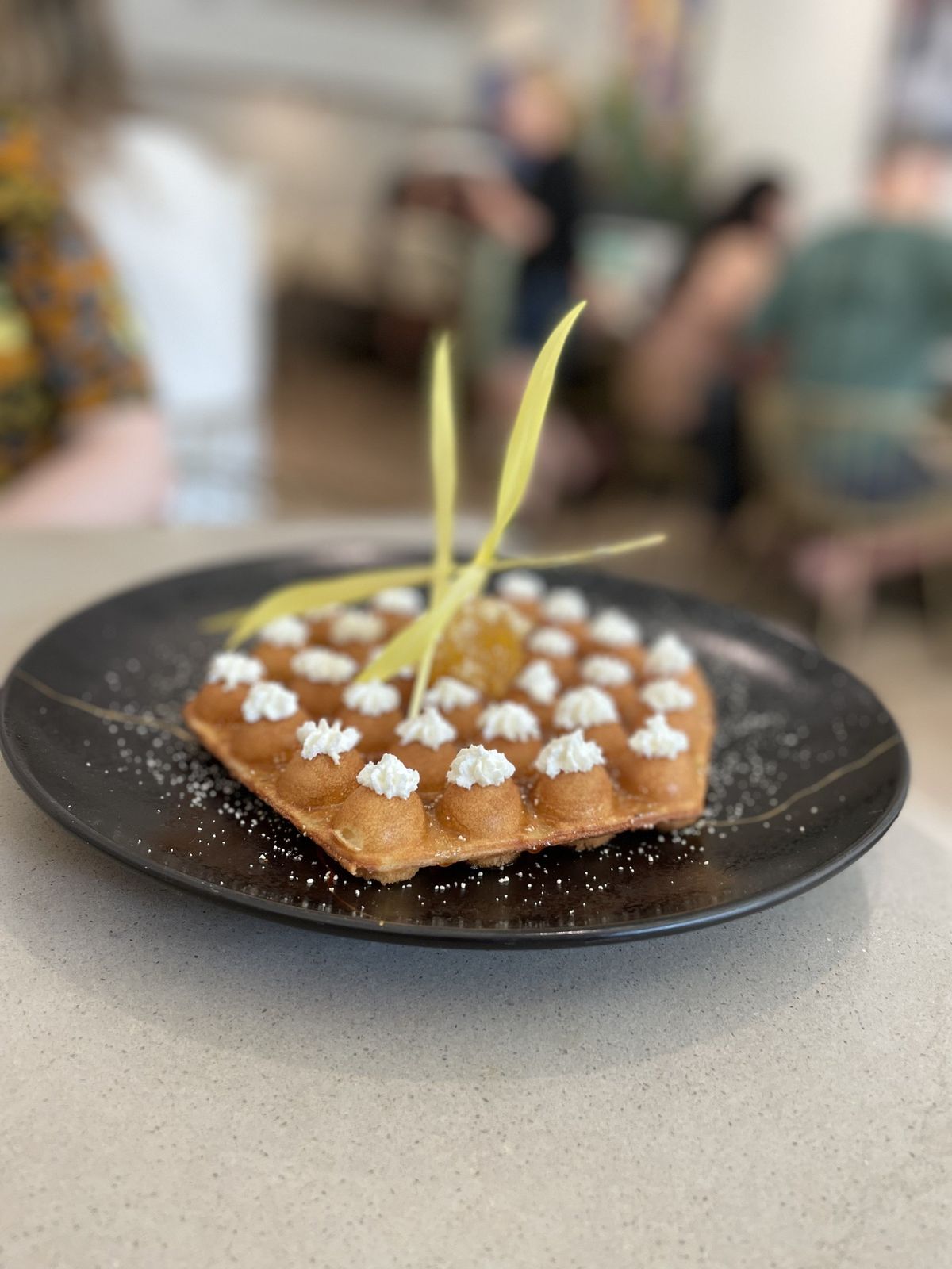 This Bubble waffle has dollops of goat cheese and a local honeycomb center. The waffle has been updated for the summer season to include lemon ricotta, huckleberry aquafaba, granola and poppyseeds.  (Lindsey Treffry/The Spokesman-Review)