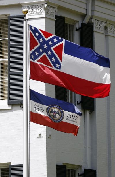 The Mississippi state flag, top, shares space with the bicentennial banner designed by the Mississippi Economic Council to recognize the state's bicentennial anniversary, Aug. 17, 2017, outside the Governor's Mansion in Jackson, Miss. Officials in one Mississippi city are voting to once again fly the Confederate-themed state flag, weeks after the mayor quietly furled it. Pontotoc Mayor Bob Peeples recently told aldermen that he issued an executive order in January to remove the flag from City Hall. Peeples says Mississippi is the only state in the country that flies a flag that is divisive among its citizens. He says he removed it to take political pressure off aldermen. (Rogelio V. Solis / AP)