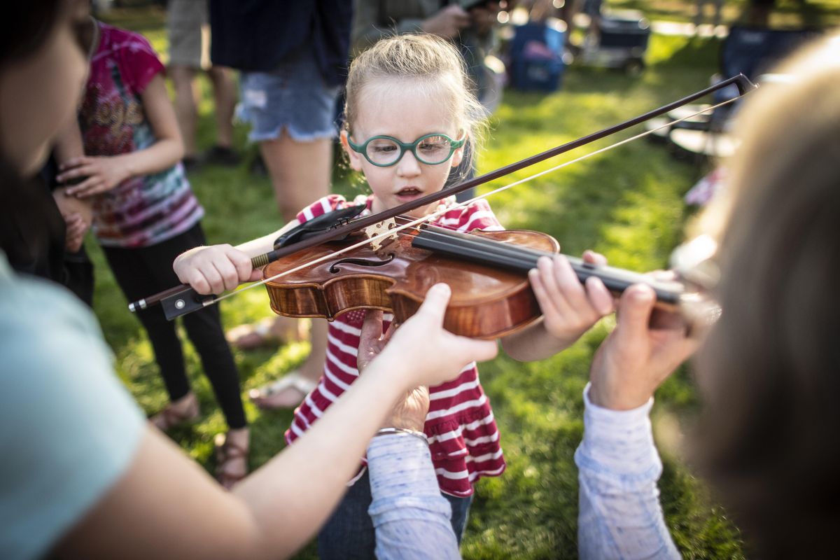 Before the annual Spokane Symphony concert in Comstock Park, Vivienne Massey 5, gives the violin a try at the Instrument Petting Zoo, Monday, Sept. 3, 2018. (Colin Mulvany / The Spokesman-Review)