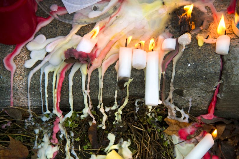 Melted and lit candles mix on the curb at the Ader family memorial at Heroy Avenue and Whitehouse Street Sunday, Feb. 12, 2012. (Colin Mulvany / The Spokesman-Review)