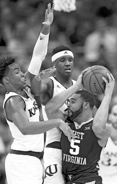 West Virginia guard Jaysean Paige (5) looks for help while covered by Kansas guard Devonte Graham, left, and forward Carlton Bragg Jr. (Orlin Wagner / Associated Press)