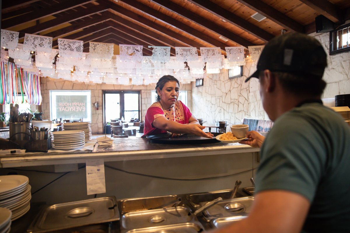 Marisela Godinez, owner of El Mesón Tequilería in Austin, Texas, serves a customer Sept. 14. She says she used to send far more leftover food to the landfill.  (New York Times)