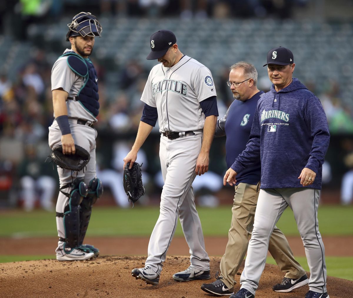 Seattle Mariners pitcher James Paxton, second from left, is escorted off the field after being hit by a ball in the first inning of a baseball game against the Oakland Athletics Tuesday, Aug. 14, 2018, in Oakland, Calif. (Ben Margot / AP)