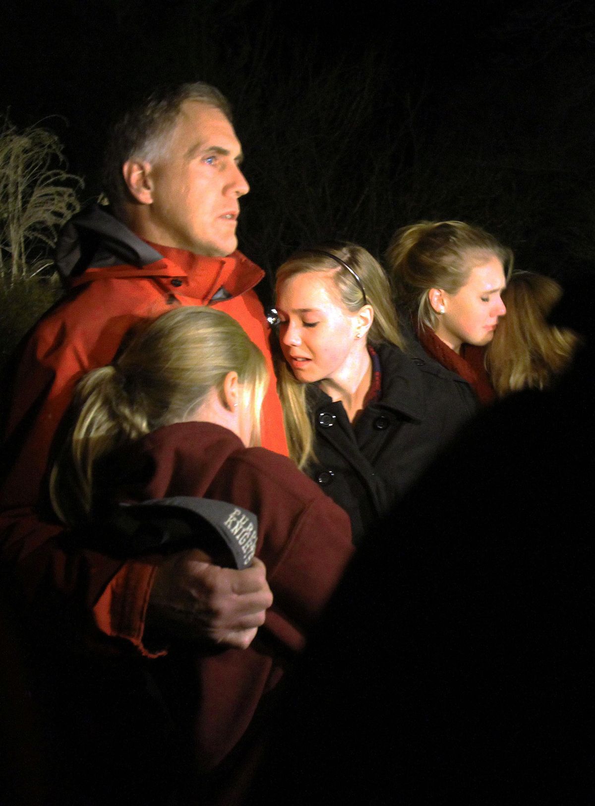 A man hugs his young daughters as they attend a vigil at Saint Rose of Lima church at Saint Rose of Lima church, Friday, Dec. 14, 2012 in Newtown, Conn. A man killed his mother at home and then opened fire Friday inside the elementary school where she taught, massacring 26 people, including 20 children, as youngsters cowered in fear to the sound of gunshots echoing through the building and screams coming over the intercom. (Frank Jr. / The Journal News)