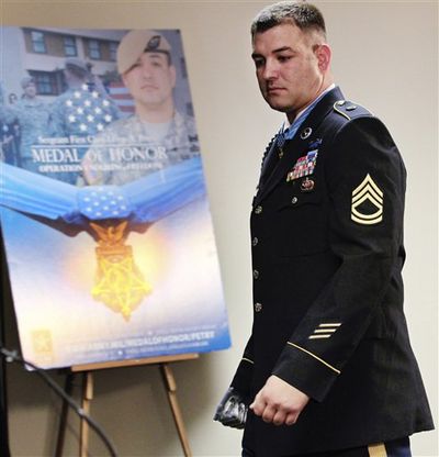 Sgt. 1st Class Leroy Arthur Petry walks past a display about his Medal of Honor award as he heads to a news conference Tuesday at Joint Base Lewis McChord, Wash. Petry was given the medal after saving the lives of fellow Army Rangers in 2008 in Afghanistan when, after being wounded by gunfire in both legs, he grabbed a grenade thrown by enemy combatants and lost his hand when he grabbed it and tried to throw it aside.  (Associated Press)