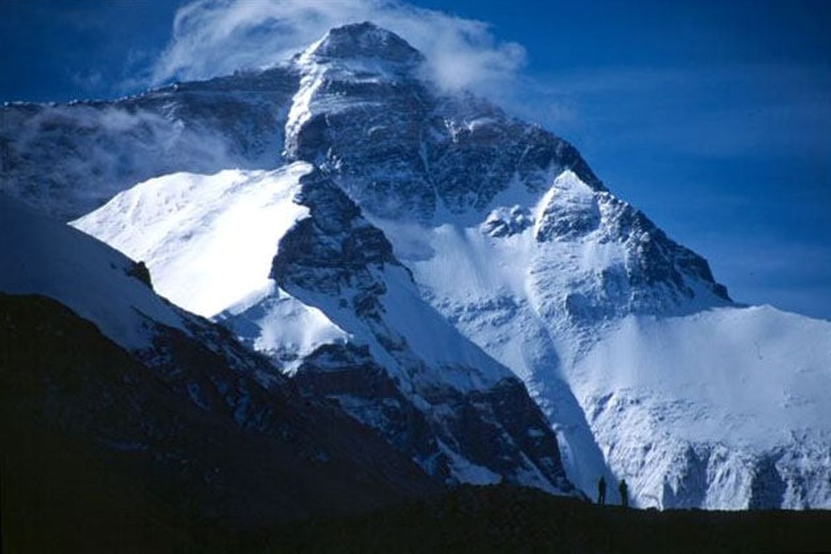Climbers on the tongue of the Rombuk Glacier are silhouetted against the north face of Mount Everest. John and Jess Roskelley climbed the northeast ridge to the left.  (Courtesy of John Roskelley)