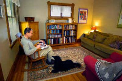 
Dave Crowner relaxes in the living room of his South Hill home while his dog, Layla, keeps him company. The home, a mere 850 square feet on the main floor, matches the couple's 