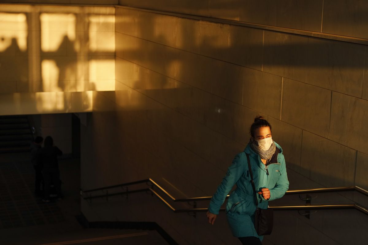 A woman wearing a face mask to help curb the spread of the coronavirus walks from the underpass up to the street during sunset in Moscow, Russia, Wednesday, Dec. 2, 2020. Russia has registered a record number of coronavirus deaths for a second straight day. Currently, there is a country-wide mask mandate and mostly mild restrictions that vary from region to region.  (Alexander Zemlianichenko)