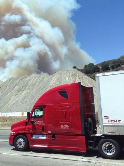 A truck drives past a heavy plume of smoke from a wildfire next to the Interstate 5 freeway in Santa Clarita, Calif., Wednesday. (Associated Press)