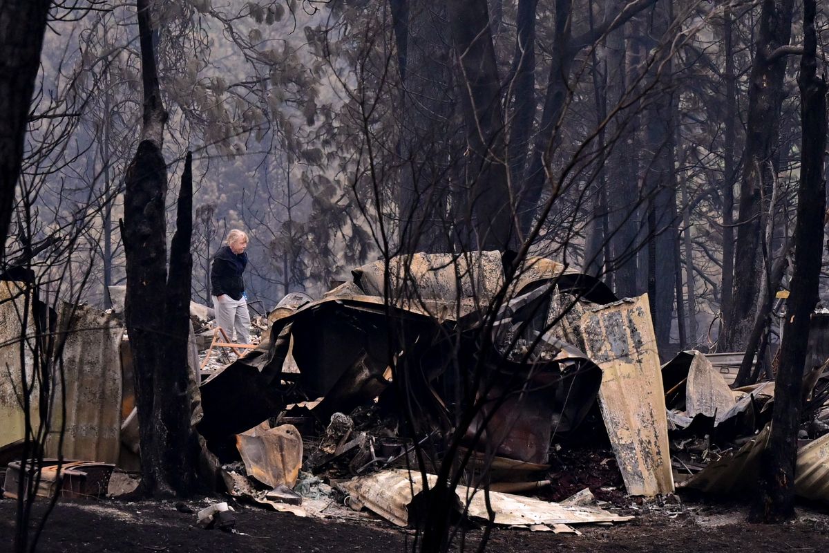 A woman walks through the remains of a structure destroyed by the Gray fire off of South Medical Lake Road after residents were allowed to return home Tuesday afternoon near Medical Lake.  (Tyler Tjomsland/The Spokesman-Review)