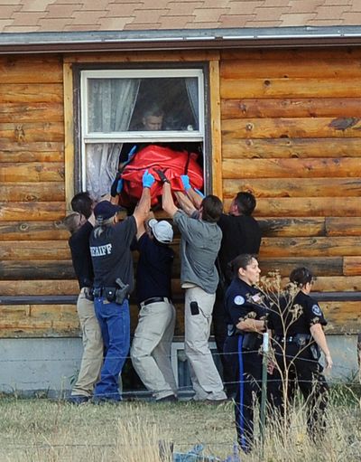Law enforcement officers remove a shooting victim’s body from a home near Montana’s Crow Reservation on Tuesday. (Associated Press)