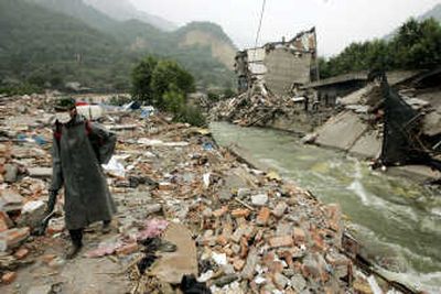 
A Chinese soldier disinfects the rubble of buildings that collapsed in the May 12 earthquake as a swelled river runs next to him Saturday in Hanwang town, Sichuan province. Associated Press
 (Associated Press / The Spokesman-Review)
