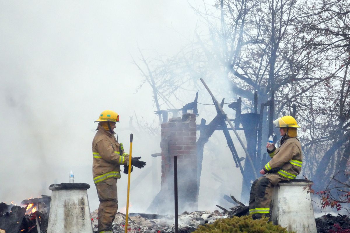 Firefighters from Spokane County Fire District 3 watch over the smoldering ruins of a rural home along U.S. 195, near Paradise Road, several miles south of Spokane, Monday, Dec. 21, 2020. The fire started shortly after 3 a.m. and the lone occupant escape safely.  (JESSE TINSLEY)