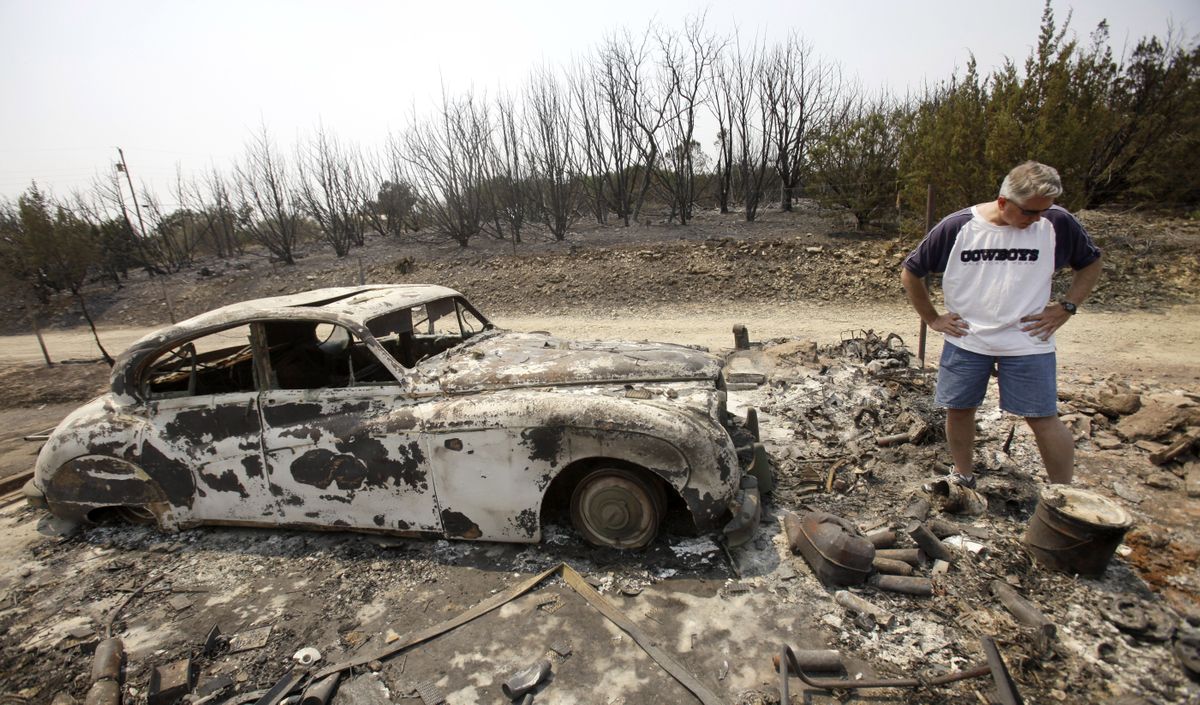 Kent Hayden looks at the remains of his parents’ garage and what was a fully restored antique Jaguar that was destroyed by a wildfire near Possum Kingdom Lake, Texas, on Saturday. (Associated Press)