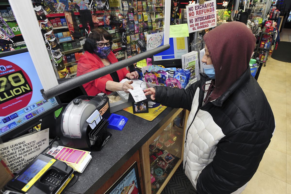 Jacqueline Donahue of Hazleton, right, buys la Mega Millions lottery ticket at the Anthracite Newsstand on Public Square, Monday, Jan. 18, 2021, in Wilkes-Barre, Pa. (Mark Moran)
