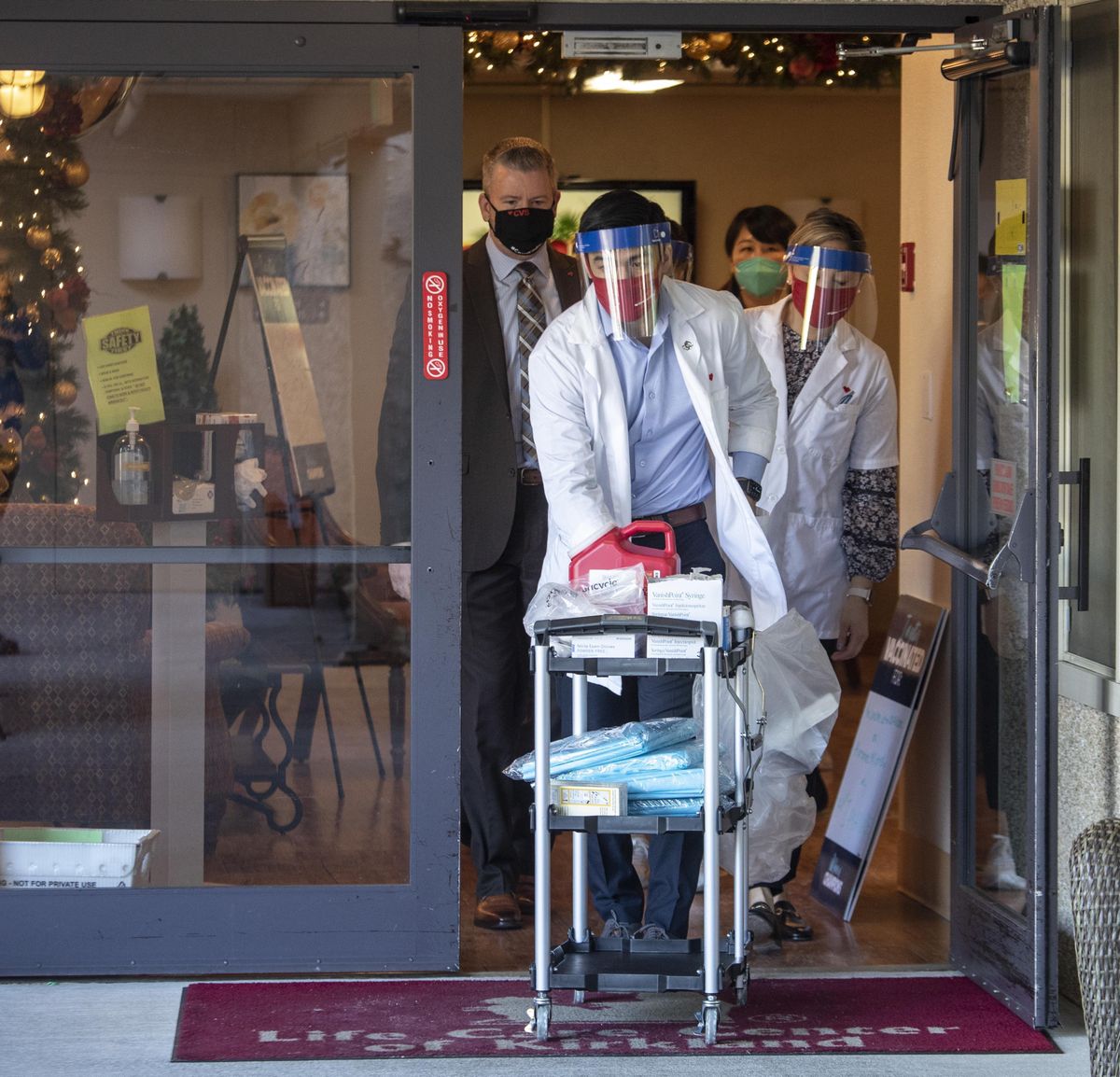 Matt Talavera, a pharmacist for CVS wheels a cart out of the Life Care Center in Kirkland, Wash., where he started giving the vaccine to employees of the Center, Monday, Dec. 28, 2020.  (Steve Ringman)