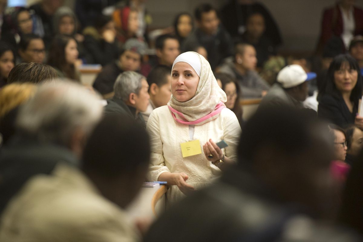 Daniah Bitar, an Arabic interpreter, stands among Arabic speaking workshop attendees and quietly translates while state Supreme Court Justice Mary Yu speaks in the mock courtroom at the Gonzaga Law School, Wednesday, Mar. 9, 2016. Immigrants and refugees from dozens of countries were invited to the law school to listen to speakers talk about the American justice system and how to avail themselves of legal services. After the opening speeches, workshop attendees split into language groups to discuss problems like domestic violence and family law. (Jesse Tinsley / The Spokesman-Review)