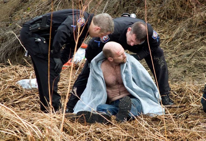 Domestic violence suspect Paul Reinhardt is attended to by Spokane Police on the eastside of Latah Creek Monday morning. Police were chasing Reinhardt when he abandoned his car at 27th and Inland Empire Way. He ended up crossing the cold waters of Latah Creek. After police arrested him, the Spokane Fire Department did a technical rescue to bring him up a cliff.   COLIN MULVANY The Spokesman-Review (Colin Mulvany / The Spokesman-Review)