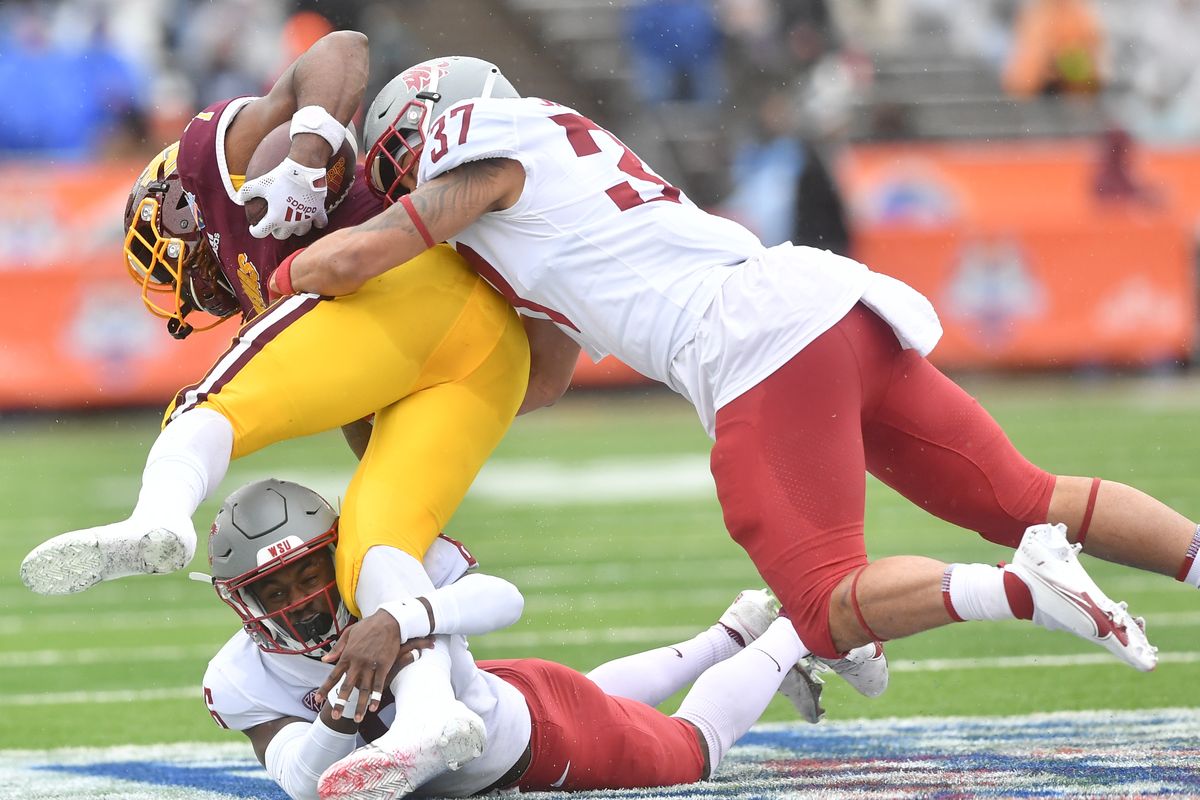Washington State Cougars cornerback Chau Smith-Wade (bottom) and linebacker Justus Rogers (right) wrap up Central Michigan Chippewas running back Lew Nichols III during the first half of a college football game on Dec. 31, 2021, at the Sun Bowl in El Paso, Texas.  (Tyler Tjomsland/The Spokesman-Review)