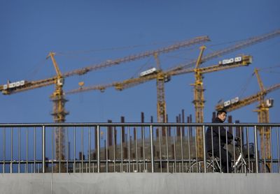 A Chinese man passes a construction site in Beijing on Jan. 5. China’s growth has made it the world’s third-largest economy.  (Associated Press / The Spokesman-Review)