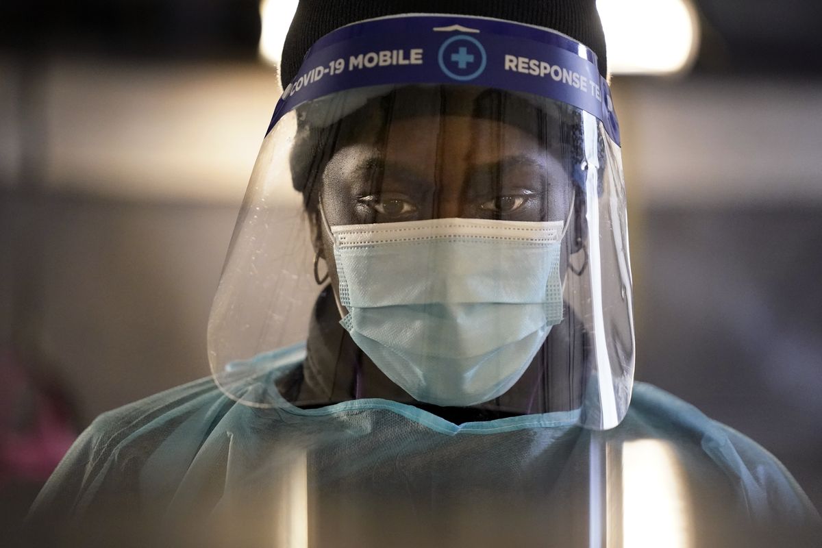 A health care worker wears personal protective equipment as she speaks Dec. 8 to a patient at a mobile testing location for COVID-19 in Auburn, Maine.   (Associated Press)