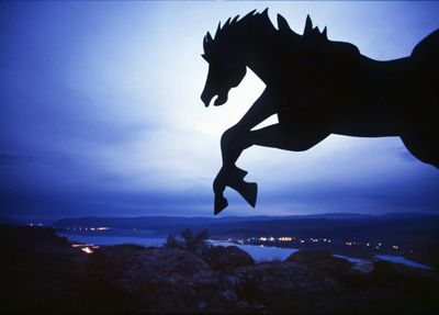 The lead horse from David Govedare’s wild horse monument sculpture forms a silhouette over the Columbia River.  (File / The Spokesman-Review)