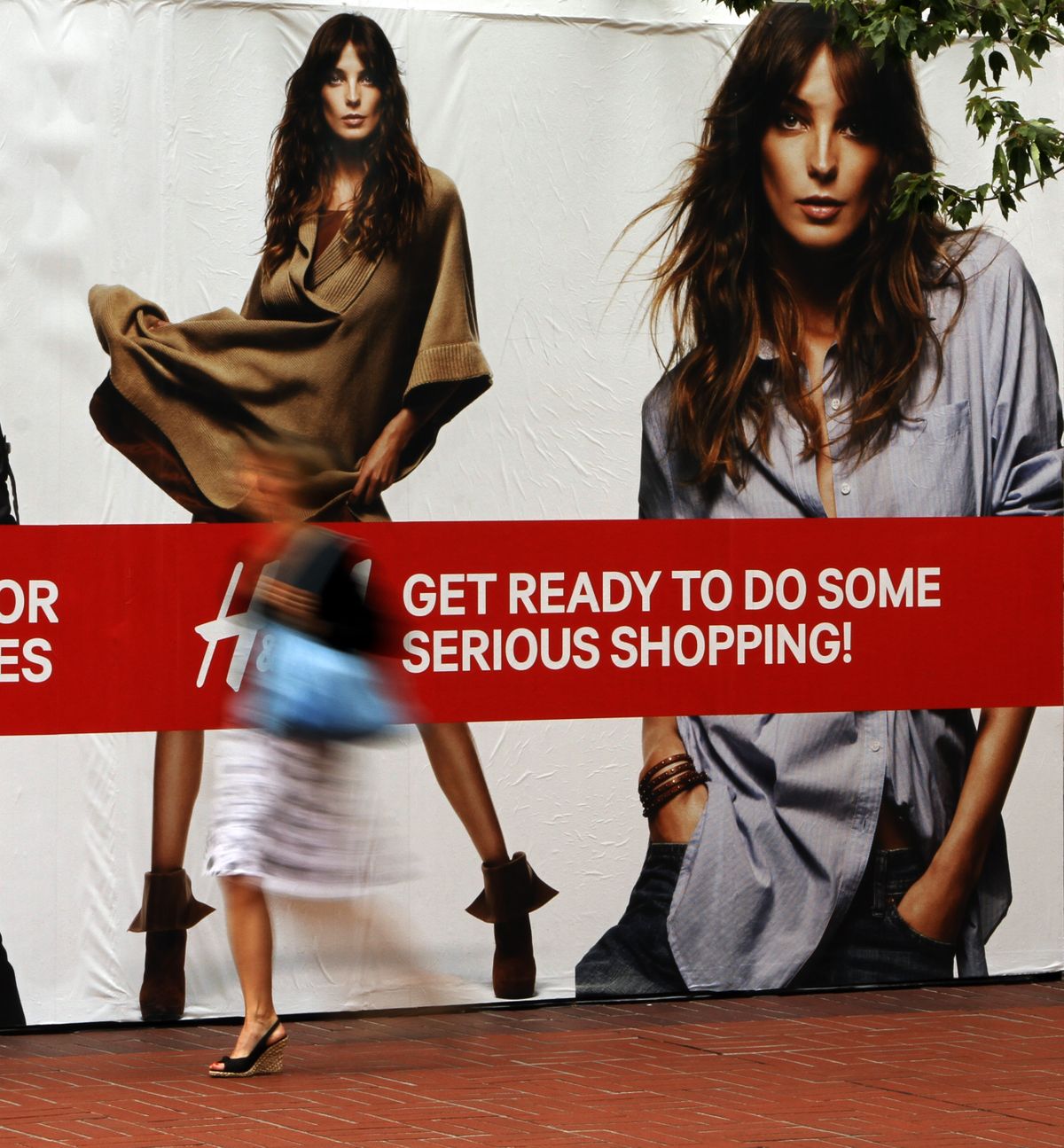 A pedestrian walks past the sign on a store under construction in Portland on Tuesday.  (Associated Press)