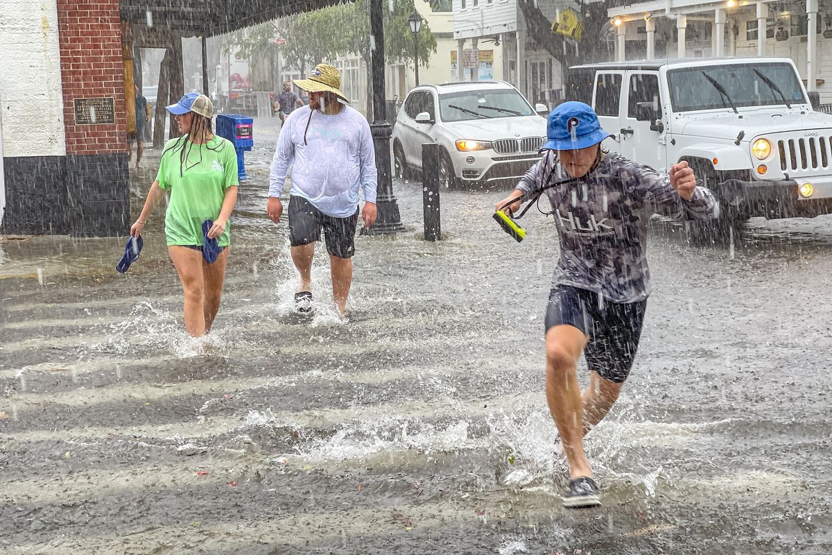 Pedestrians dash across the intersection of Greene and Duval streets as heavy winds and rain associated with Tropical Storm Elsa passes Key West, Fla., on Tuesday, July 6, 2021. The weather was getting worse in southern Florida on Tuesday morning as Tropical Storm Elsa began lashing the Florida Keys, complicating the search for survivors in the condo collapse and prompting a hurricane watch for the peninsula