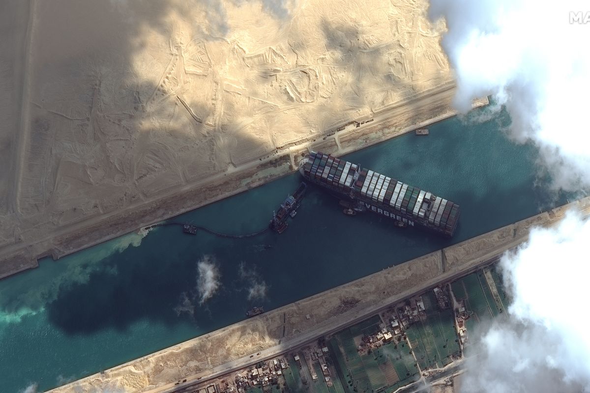 This satellite image from Maxar Technologies shows the cargo ship MV Ever Given stuck in the Suez Canal near Suez, Egypt, Friday, March 26, 2021. A maritime traffic jam grew to more than 200 vessels Friday outside the Suez Canal and some vessels began changing course as dredgers worked frantically to free a giant container ship that is stuck sideways in the waterway and disrupting global shipping.  (©Maxar Technologies)