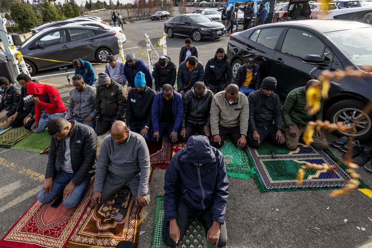 Muslim drivers face toward Mecca and pray during Ramadan at Seattle-Tacoma International Airport’s staging and dispatch lots, April 5, in Seattle. Drivers waiting for ride assignments here are calling for access to clean restrooms, running water and a sheltered prayer area.  (Ken Lambert/The Seattle Times)
