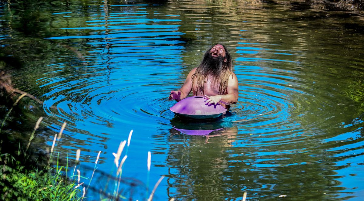 Adam Foote, aka “Ethereal In E,” plays the handpan in the middle of a tributary of the Spokane River in Coeur d’Alene on Wednesday.  (Kathy Plonka/The Spokesman-Review)