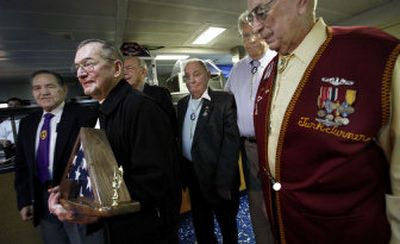 
William Blair, second from left, of Suffolk, Va., holds a flag presented to him by former prisoners of war of World War II on Wednesday aboard the USS Bataan in Norfolk, Va. 
 (Associated Press / The Spokesman-Review)