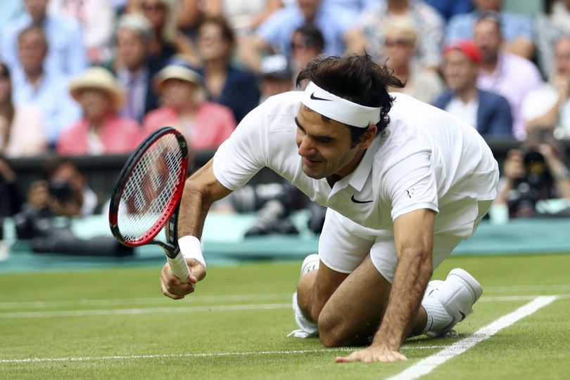 Seven-time Wimbledon champion Roger Federer  falls over during the fifth set of his semifinal defeat against  Milos Raonic. (Clive Brunskill / Associated Press)