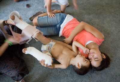 Sahrada Wellborn, 11, cuddles with her brother Neiko, 2, while mom Tiffany Oakes removes Neiko’s “boots” that keep his feet from bending downward. (Associated Press / The Spokesman-Review)