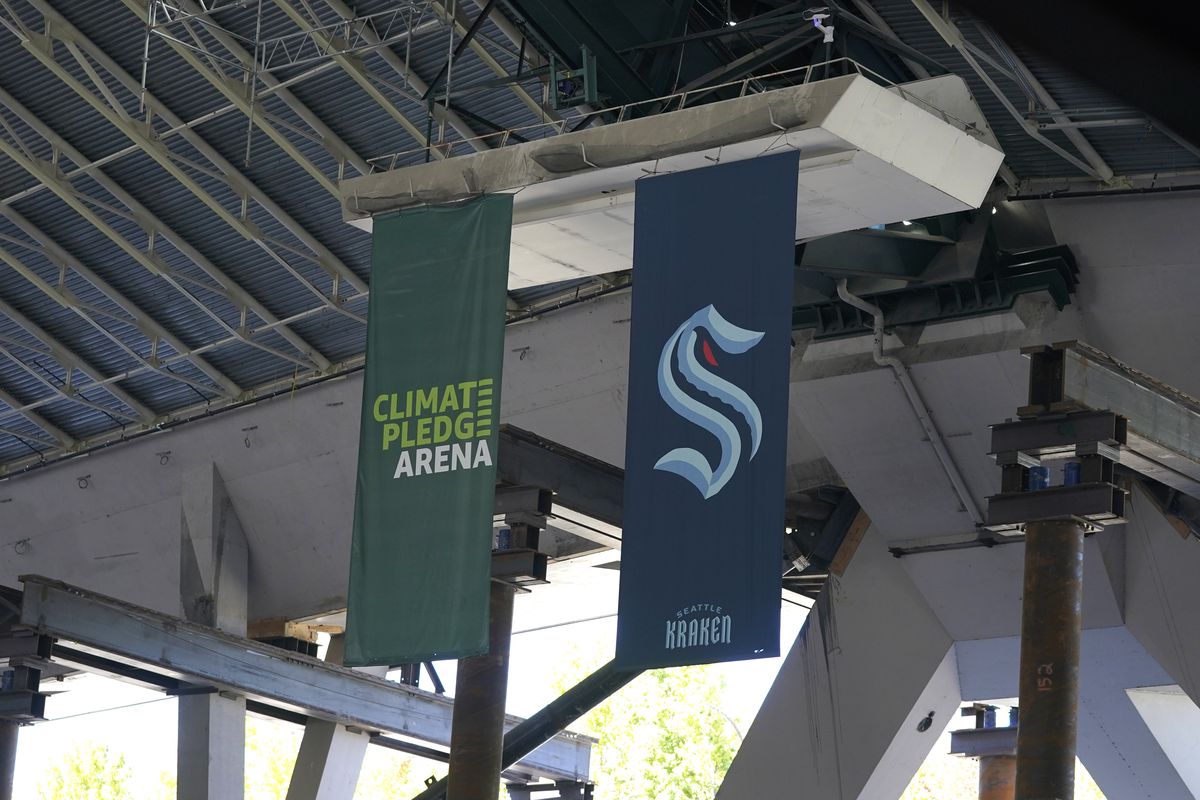 Flags for the Seattle Kraken NHL hockey team and the Amazon-sponsored Climate Pledge Arena hang in the rafters Tuesday, Sept. 1, 2020, as work continues in Seattle on the home of the Seattle Kraken NHL hockey team. Sometime in the late summer or early fall of 2021, the Kraken will open the new facility – at a cost that will likely total $1 billion by the time it’s done – and become the NHL’s 32nd franchise. (Ted S. Warren)