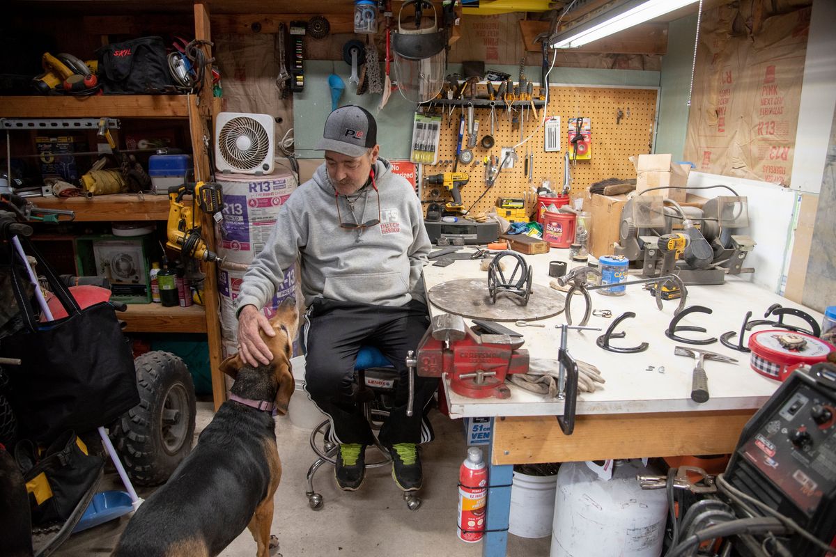 Greg Soumokil pets his dog Duchess in his home shop Tuesday, May 17, 2022, at his Spokane Valley home. He was the first heart patient to leave Sacred Heart and live at home with an artificial heart while he waited for a transplant of a heart and a kidney and has spent his time at home and in recovery doing crafts in his tiny shop. Now on the mend after organ transplants this past fall, he hopes to keep busy with his crafts and check off some of his bucket list items, which include boating and traveling.  (Jesse Tinsley/The Spokesman-Review)