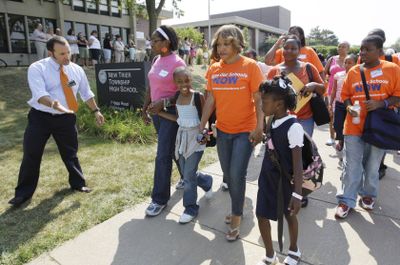A school official welcomes Chicago public school students and their parents who protested unequal school funding by filling out applications in the suburban New Trier High School on Tuesday.  (Associated Press / The Spokesman-Review)