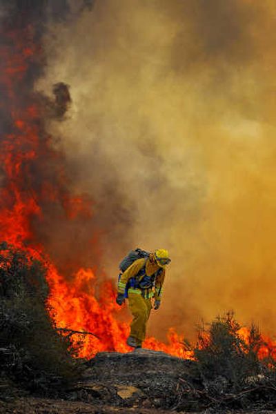 A firefighter walks out of a brush fire burning out of control in the Santa Ynez Mountains near Goleta, Calif., on Saturday. Associated Press
 (Associated Press / The Spokesman-Review)