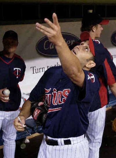 
Minnesota pitcher Juan Rincon flips an autographed ball back to a fan prior to Friday's game against the Texas Rangers. 
 (Associated Press / The Spokesman-Review)